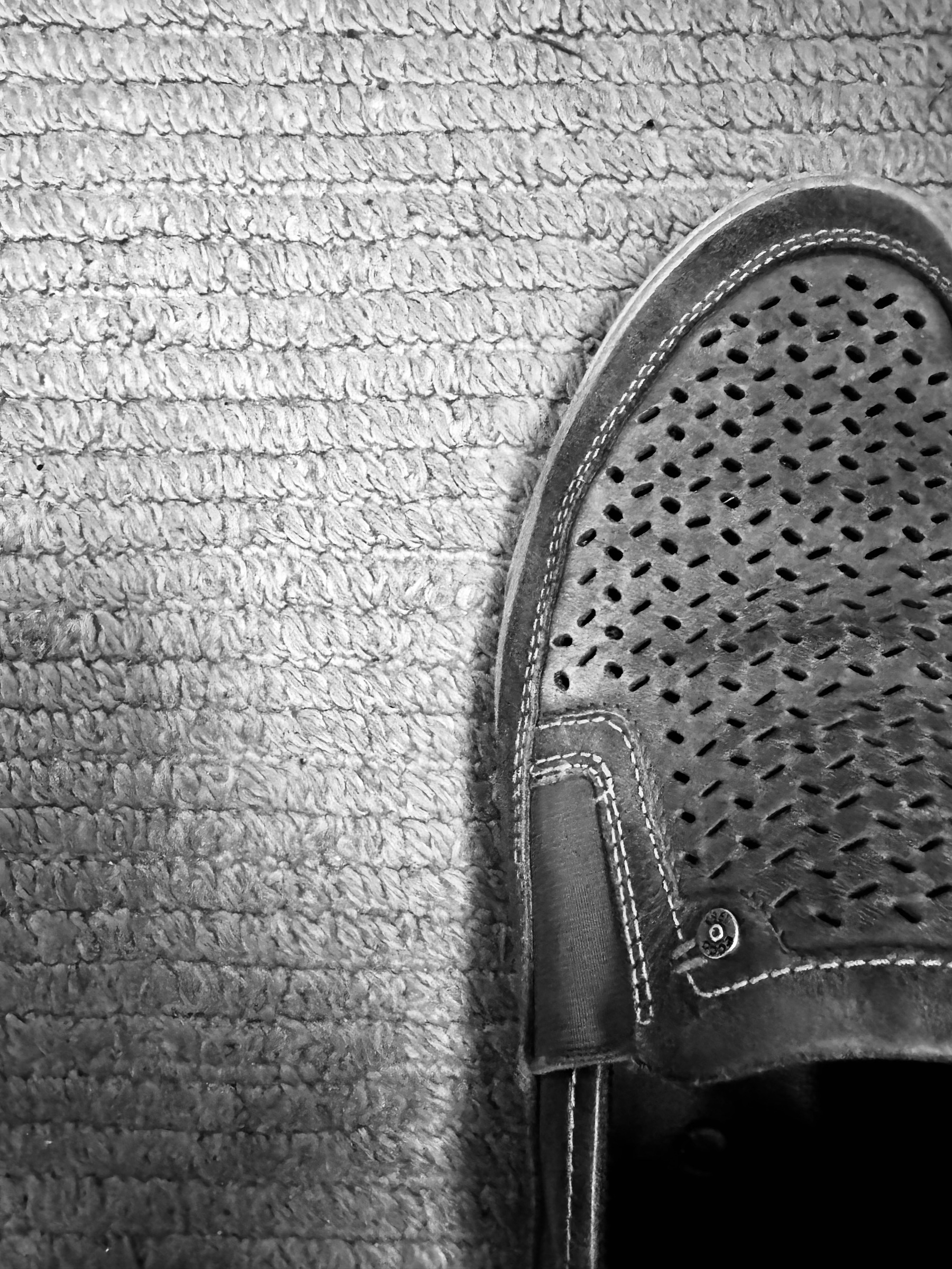 Auto-generated description: A perforated slip-on shoe is placed on a textured carpet.